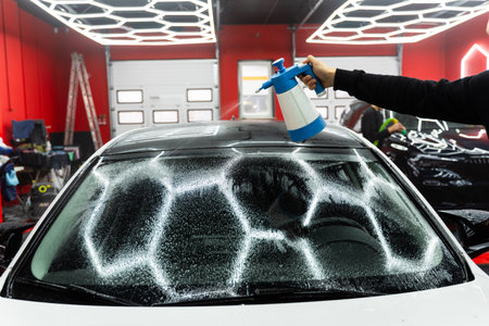 Windshield preparation with a special solution before film application. Detailer spray a glass prep liquid to remove dust, grease, and debris before applying protective filmの写真素材