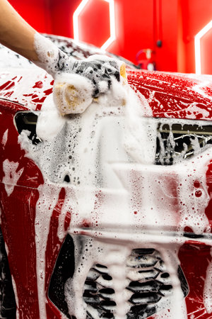 Sponge washing to clean every panel without scratching or damaging the paint. Hand car wash detailing sponge stage removes dirt and debris, leaving the car paint smooth and glossyの写真素材