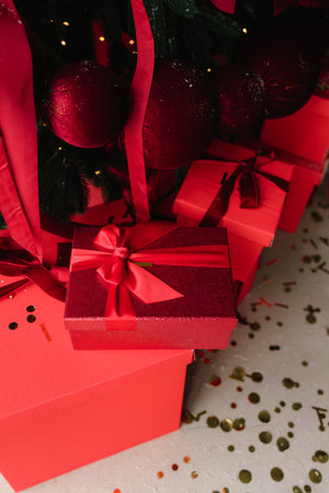 Red Christmas presents under tree with festive lights and ornamentsの写真素材