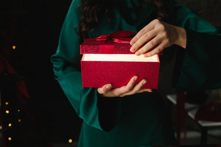 Soft golden lighting from red Christmas gift in handsの写真素材