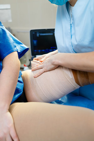 Compression socks applied by medical professional after vascular treatment