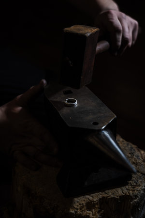 Jewelry craftsman shaping ring by hammering on anvil