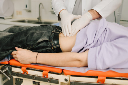 Kidney palpation by urologist for male patient lying on back with discomfortの写真素材