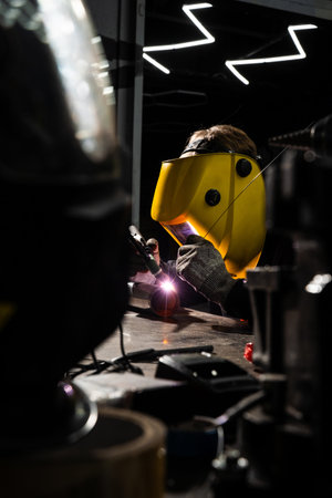 Worker welds metal with TIG process using tungsten electrode and argon