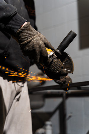 Metal cutting with angle grinder by worker in industrial environment