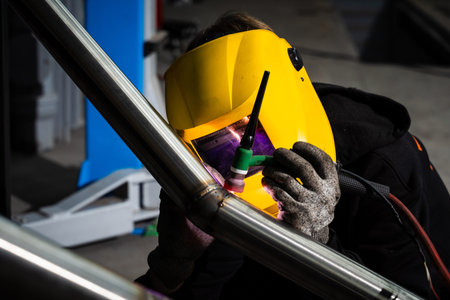 Welder performs precision TIG welding on automotive exhaust pipe