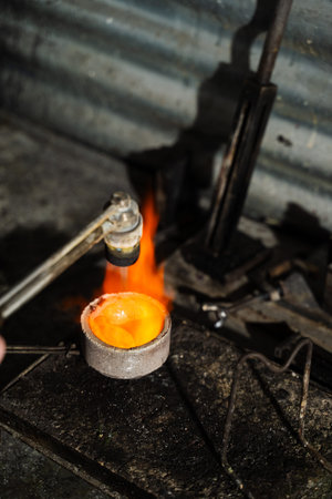 Jeweler heating gold in crucible with gas torch flame