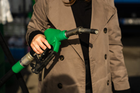 Fuel station close-up with hand on petrol nozzleの写真素材
