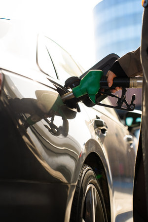 Hand gripping fuel pump nozzle while refueling carの写真素材