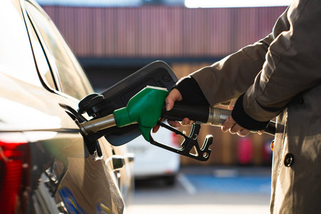 Hand holding gasoline nozzle while refilling vehicle tankの写真素材