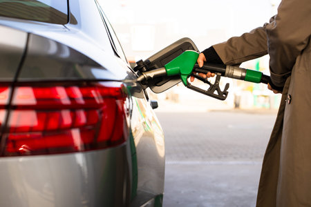 Fuel pump inserted into tank during refueling. Close-up of hand refilling vehicle with gasoline