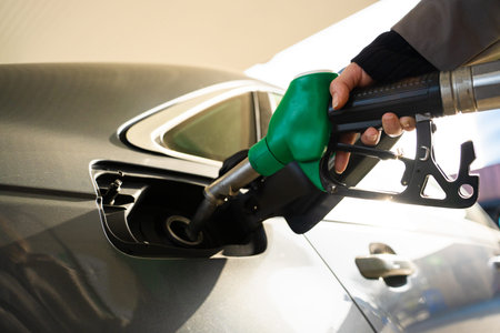 Petrol pump nozzle inserted into vehicle fuel tank close-up
