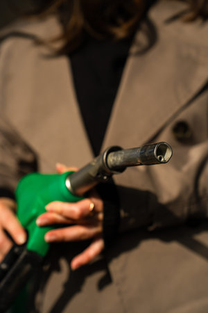 Hand holding gasoline nozzle at fuel station close-up. Driver refueling car using gasoline pumpの写真素材