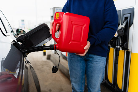 Close-up of red fuel canister pouring gasoline into vehicle tank