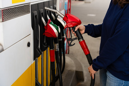 Close-up of refueling car with hand on fuel pump nozzle