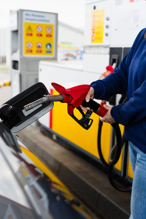 Hand holding fuel pump while refilling car at gas station
