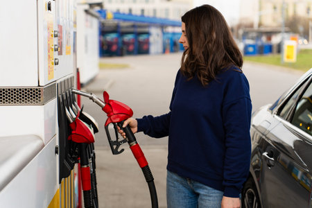 Woman refueling car while checking fuel price on gas pump display