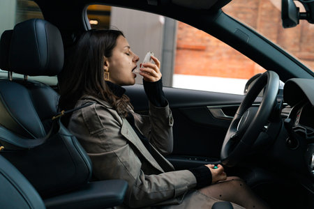 Person inhaling medication from asthma inhaler for respiratory support in car