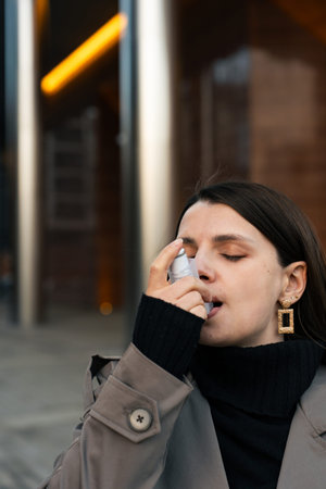 Female using asthma inhaler for asthma symptom relief outside
