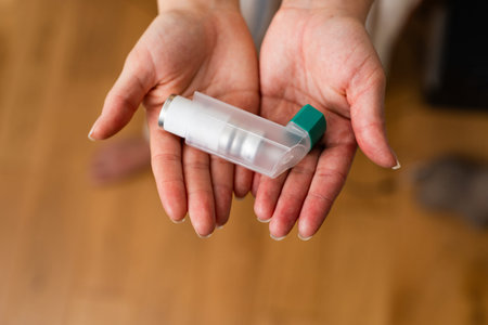 Hand holding asthma inhaler isolated on white background close up