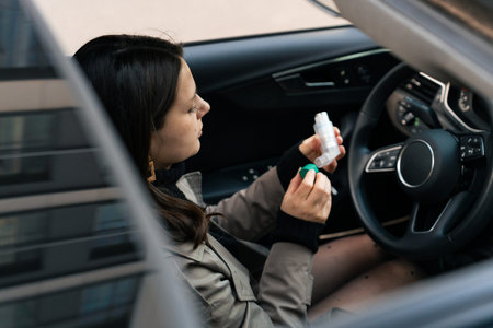 Young woman using asthma inhaler for breathing relief while sitting in car
