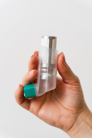 Male hand holding asthma inhaler close up on white background
