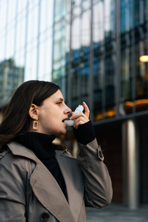 Woman taking asthma inhaler for respiratory support in outdoor setting