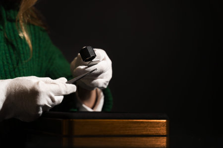 Gemologist inspecting diamond with tweezers and loupe to evaluate clarity and cut quality