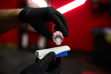Ceramic Coating and Paint Protection. Close-up applying ceramic coating liquid to applicator pad. Expert detailer prepares to apply nano-ceramic coating using specialized applicator block.