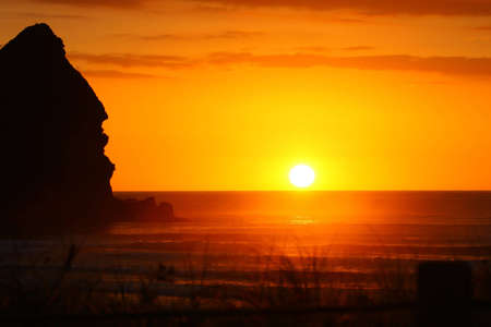 Last rays of a gorgeous sunset at Piha beachの写真素材