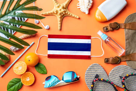 Accessories for beach holidays around a protective mask with the flag of Thailand. Concept of leisure at sea during a pandemic. Top view.の写真素材