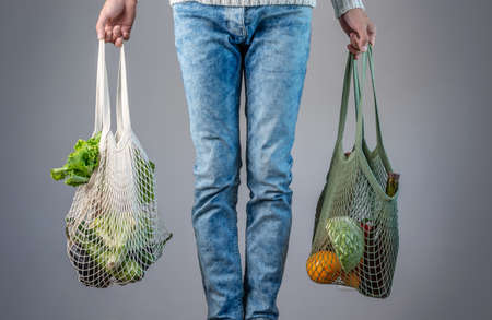 A modern young man is holding a string bags with purchases. Concept of eco-friendly behavior, the...