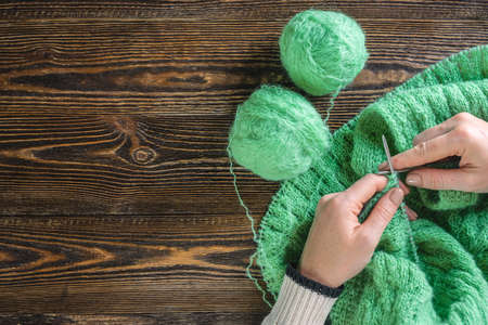 Woman is knitting a cozy warm sweater with needles. Concept of hobbies and creating handmade things....