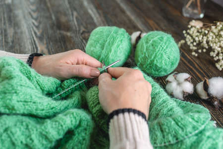 Woman is knitting a cozy warm sweater with needles. Concept of hobbies and creating handmade things.の写真素材