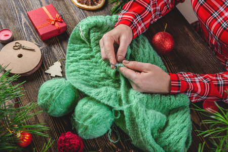 A woman is knitting a warm cozy sweater as a present. Concept of creating handmade gifts for New year and Christmas.の写真素材