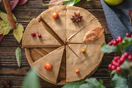 Brown mousse cake minimally decorated with autumn symbols on a wooden background. Concept of seasons and autumn mood.の写真素材