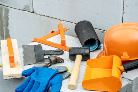 Set of construction tools on the background of a wall of aerated concrete blocks on a building site.