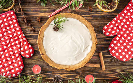 Homemade tart with white cream on a wooden table decorated with pine branches. Festive table decoration for Christmas and new yearの写真素材