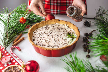 Homemade tart decorated with cocoa on a white table decorated with pine branches. Festive table decoration for Christmas and new yearの写真素材