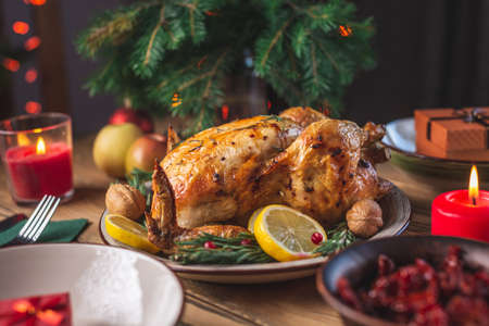 Crispy baked chicken with rosemary and berries on a wooden table. Traditional Christmas dish for a festive dinner in a rustic styleの写真素材
