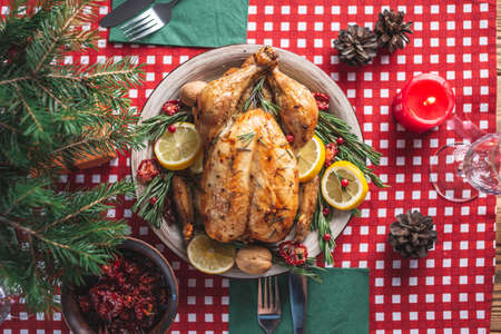Crispy baked chicken with rosemary and berries on a wooden table. Traditional Christmas dish for a festive dinner in a rustic style. Top viewの写真素材