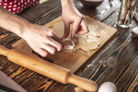 Woman making delicious homemade cookies in the shape of heart in her kitchen. Concept of fresh...