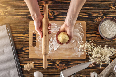 Woman is holding raw dough and rolling pin in her hands for making delicious homemade ginger cookies...