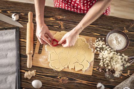 Woman making delicious homemade cookies in the shape of heart in her kitchen. Concept of fresh homemade cakes or a surprise for Valentine's day.の写真素材