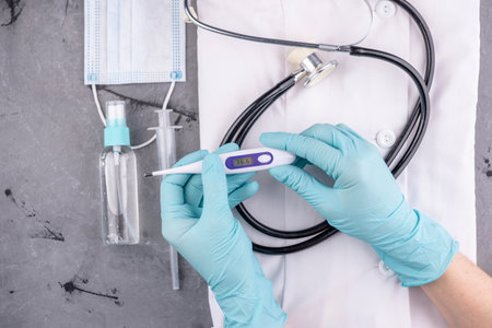 Tools and protective equipment for the doctor on a gray background. Hands with gloves are holding a...