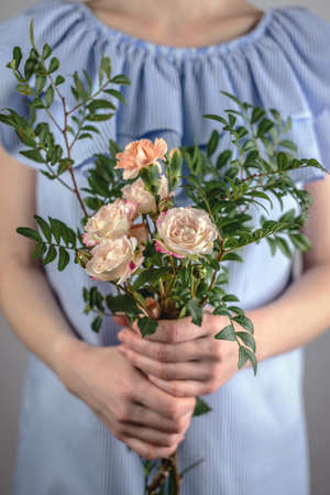 A woman in a blue dress is holding a small tenderness bouquet of flowers. Concept of spring, summer nice romantic mood.の写真素材
