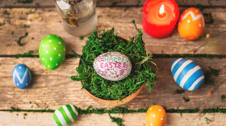 Bright colorful Easter eggs and rabbit ears on a background made of old wooden boards covered with...