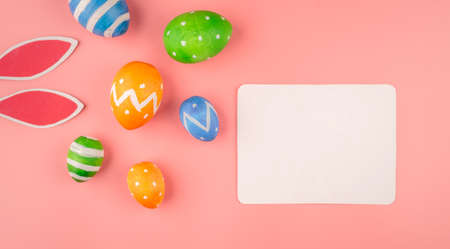 Bright Easter card with colorful eggs, paper rabbit ears on a pink background. Copy space and top...