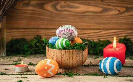Bright colorful Easter eggs on a background made of old wooden boards covered with green moss.