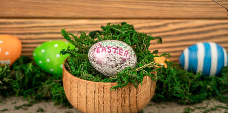 Bright colorful Easter eggs on a background made of old wooden boards covered with green moss.